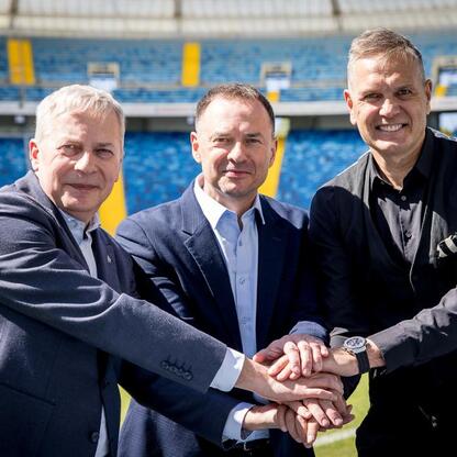 Trzech mężczyzn stojących razem przed Superauto.pl Stadionem Śląskim, symbolizujących wspólne wysiłki organizacyjne dla Mistrzostw Europy w Lekkoatletyce 2028. (wygenerowano przez AI)