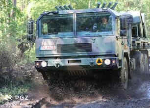 Jelcz military truck driving through muddy forest road, kicking up a cloud of mud. (wygenerowano przez AI)