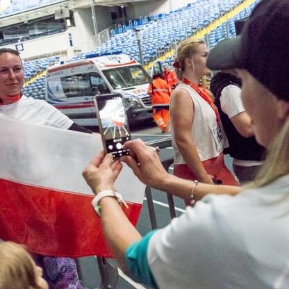 Bieg dla Flagi w Tauron Parku Śląskim, uczestniczka z flagą Polski, ambulans w tle. (wygenerowano przez AI)