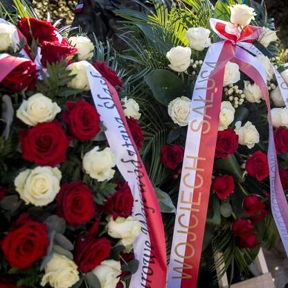 Floral arrangement with red and white roses, greenery, and ribbons commemorating the 105th anniversary of the Third Silesian Uprising and the Day of the Polish Flag at Tauron Park Śląskim. (wygenerowano przez AI)