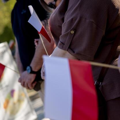 Zdjęcie przedstawia osobę trzymającą flagę Polski na Śląskim Capstrzyku w Tauron Parku Śląskim. (wygenerowano przez AI)