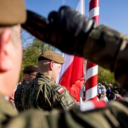 Na Tauron Parku Śląskim żołnierz salutuje, tło: flaga Polski, uroczystość 105. rocznicy III Powstania Śląskiego. (wygenerowano przez AI)