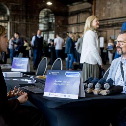 Silesian Center for Entrepreneurship booth at the former Cynk Walcownia Museum in Katowice during a conference on reviving industrial heritage through tourism and business. (wygenerowano przez AI)