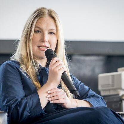 Joanna Bojczuk, członek Zarządu Województwa Śląskiego, prowadzi panel dyskusyjny na konferencji o rewitalizacji przemysłowych terenów. (wygenerowano przez AI)