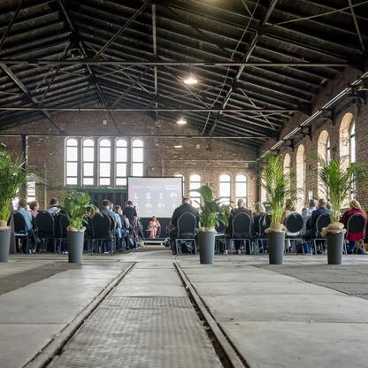 Widoczna jest sala konferencyjna w Muzeum Hutnictwa Cynku Walcownia w Katowicach, gdzie odbywa się spotkanie o rewitalizacji przemysłowych terenów. (wygenerowano przez AI)