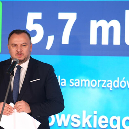 Mężczyzna w garniturze przemawia na podium, promując program poprawy jakości powietrza w Śląsku. (wygenerowano przez AI)