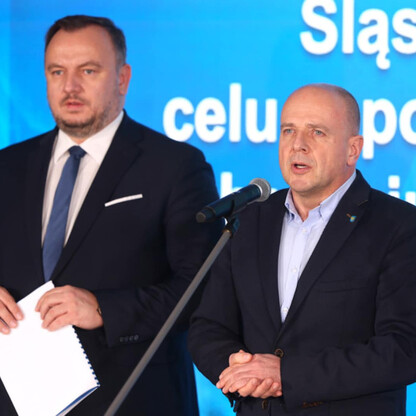 Podczas konferencji dotyczącej poprawy jakości powietrza województwa śląskiego, dwie osoby stoją na podium, jedna przemawia do mikrofonu, druga trzyma dokument. (wygenerowano przez AI)