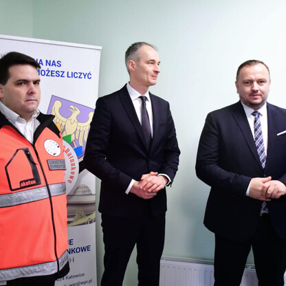 Trzech mężczyzn stoi przed banerem z napisem 