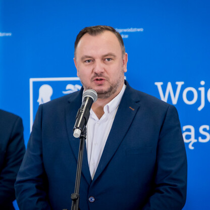 Mężczyzna w ciemnym garniturze przemawia na podium, podczas uroczystego wręczenia umów dla LGD w Silesia. (wygenerowano przez AI)