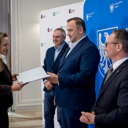Wicemarszałek Grzegorz Boski wręcza dokumenty przedstawicielom LGD podczas uroczystego wręczenia umów finansowych w ramach LEADER. (wygenerowano przez AI)