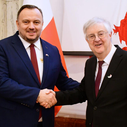 Dwa urzędnicy witań w obliczu flagi Walii, symbolizujące odnowienie Memorandum o współpracy Śląska i Walii. (wygenerowano przez AI)