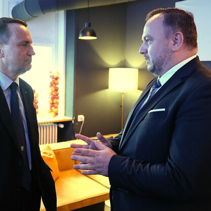 Dwa mężczyźni w strojach formalnych rozmawiają w nowoczesnym pomieszczeniu podczas Światowego Forum Ekonomicznego w Davos. (wygenerowano przez AI)