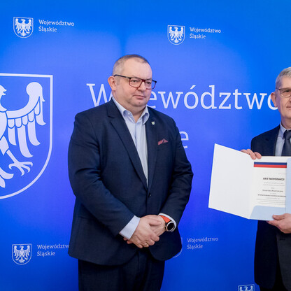 Dwóch mężczyzn prezentuje dokument na tle logo Województwa Śląskiego. (wygenerowano przez AI)