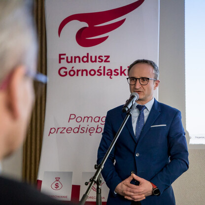 Grzegorz Boski, Wicemarszałek Województwa Śląskiego, przemawia na podium podczas konferencji Fundusz Górnośląski, promując projekty Global Silesia i InterSilesia. (wygenerowano przez AI)