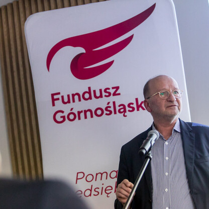 Mężczyzna przemawia na podium Funduszu Górnośląskiego, wspierając rozwój eksportu dla małych i średnich przedsiębiorstw w regionie. (wygenerowano przez AI)