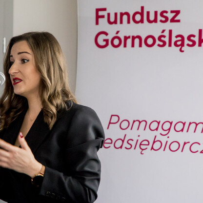Kobieta przemawia w mikrofonie na konferencji Funduszu Górnośląskiego SA, wspierając rozwój eksportu małych i średnich przedsiębiorstw w Śląsku. (wygenerowano przez AI)