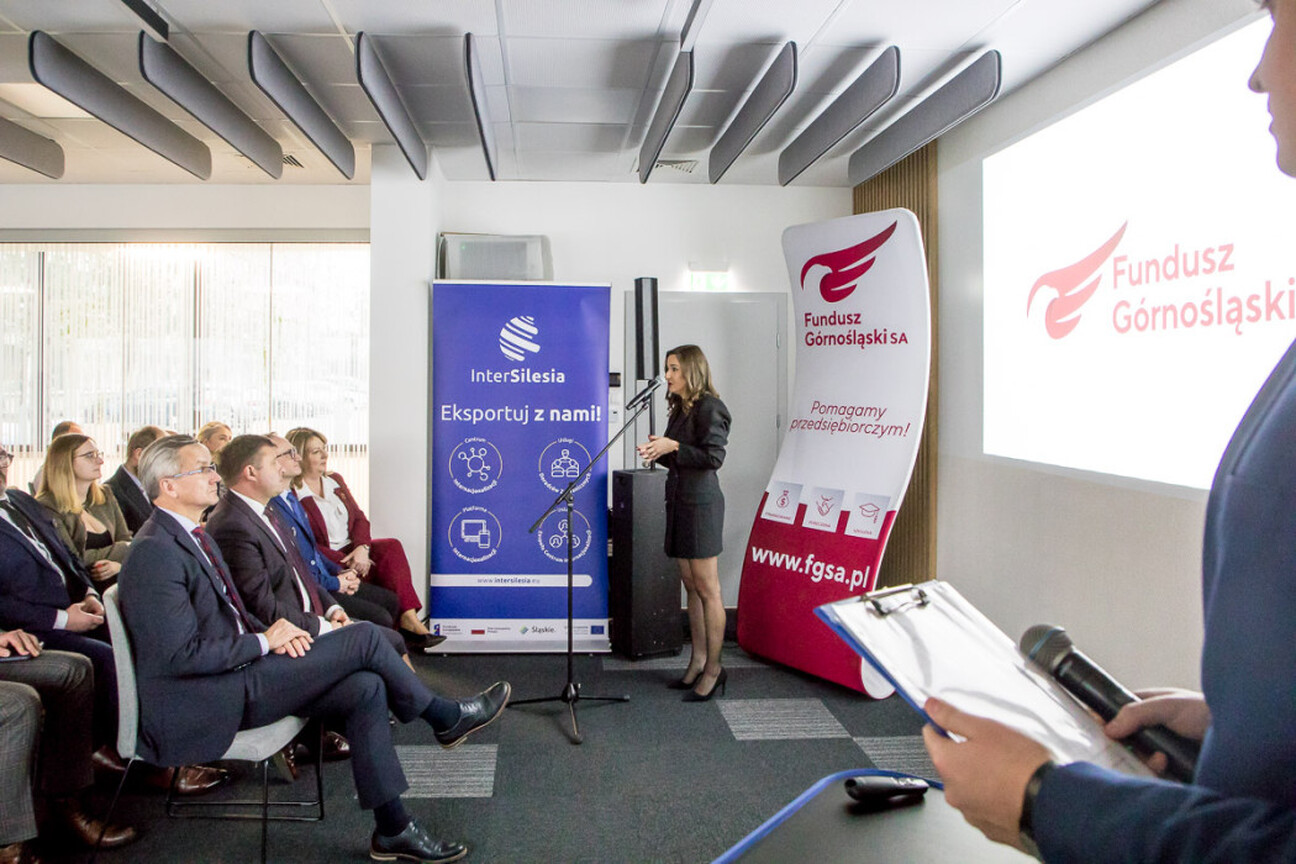 Podczas konferencji w ramach projektu "InterSilesia" przedstawicielka Funduszu Górnośląskiego SA prowadzi prezentację na podium. (wygenerowano przez AI)