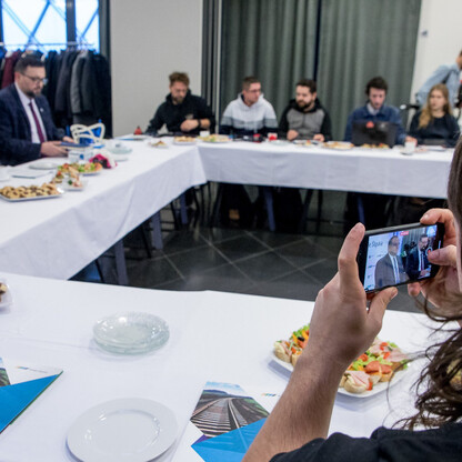 Grupa ludzi siedzi w konferencyjnym pomieszczeniu, omawiając sukces Kolei Śląskich. (wygenerowano przez AI)