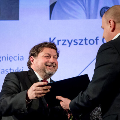 Podczas uroczystości wręczenia nagród Marszałka Województwa Śląskiego Culture Awards, trzech mężczyzn w garniturach uczestniczy w ceremonii wręczenia certyfikatów. Tło prezentuje nazwy i kategorie lau (wygenerowano przez AI)
