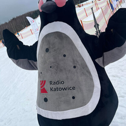 Wielki pingwin w kostiumie na śnieżnym stoku, symbol zimowego festynu w Beskidach. (wygenerowano przez AI)