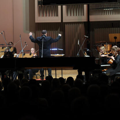 Formalny koncert noworoczny w Filharmonii Śląskiej, gdzie dyrygent prowadzi orkiestrę, a publiczność śledzi muzykę. (wygenerowano przez AI)