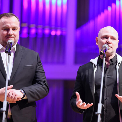 Dwie osoby na scenie z mikrofonami, uczestniczące w koncercie 
