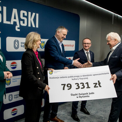 Grzegorz Boski, wicemarszałek województwa, prezentuje symboliczne czeki na Stadionie Śląskim. (wygenerowano przez AI)