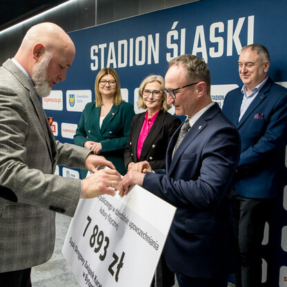 Grzegorz Boski, wicemarszałek Województwa Śląskiego, prezentuje symboliczne czeki na Stadionie Śląskim. (wygenerowano przez AI)