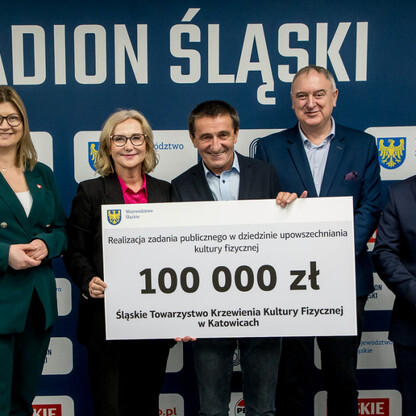 Grzegorz Boski, wicemarszałek, wręcza symboliczne czeki przed Stadionem Śląskim. (wygenerowano przez AI)