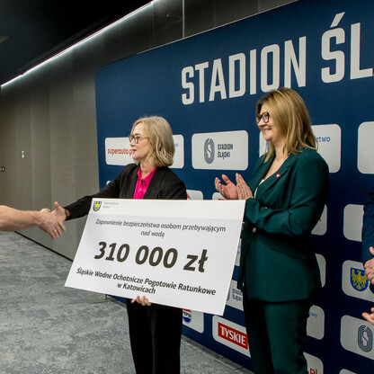 Symboliczna transferacja czeków na Stadionie Śląskim, wspieranie kultury fizycznej i bezpieczeństwa publicznego. (wygenerowano przez AI)