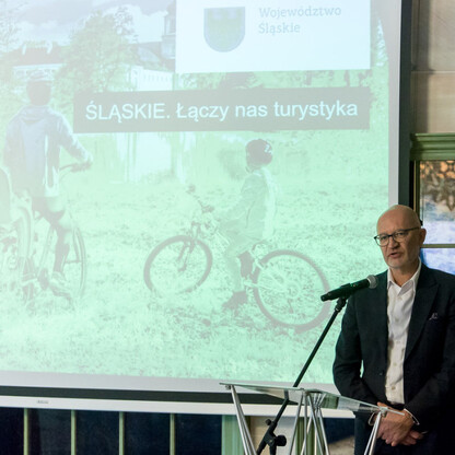 Na podium mówiący prezydent Mirosław Mazur, podkreślający problem illegalnego składowania odpadów. (wygenerowano przez AI)