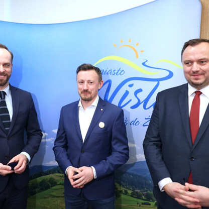 Trzech mężczyzn w garniturach przed logo Wisły, symbolizującego miasto i jego rozwój. (wygenerowano przez AI)