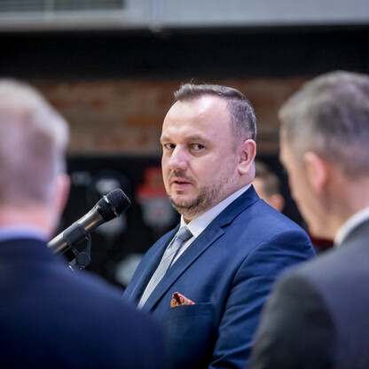 Grupa mężczyzn w formalnym stroju podczas spotkania w Kopalni Ignacy w Rybniku, związana z partnerstwem między samorządem województwa śląskiego, lokalnym rządem i Kopalnią Ignacy. (wygenerowano przez AI)