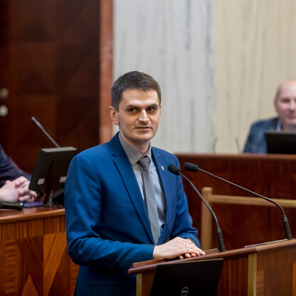Geodetyczna konferencja w Katowicach, uczestnicy w niebieskich garniturach, dyskutują o topografii i rolnictwie. (wygenerowano przez AI)