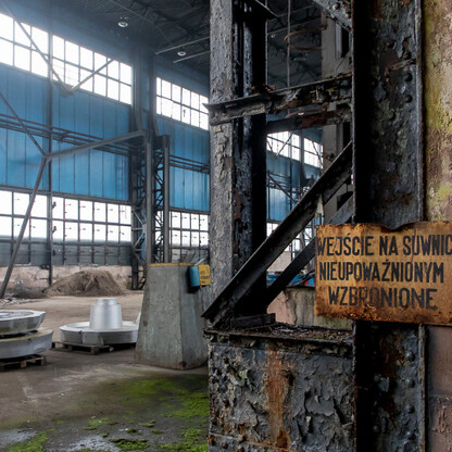 Abandoned industrial interior, weathered walls, moss-covered floor, restricted access sign, evoking decay and abandonment. (wygenerowano przez AI)