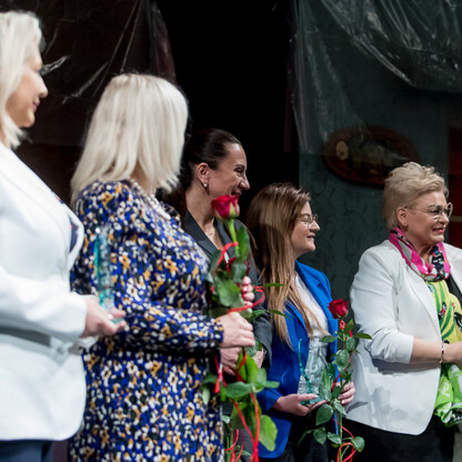 Grupa kobiet wymienia kwiaty i rozmawia podczas ceremonii wręczenia nagród 
