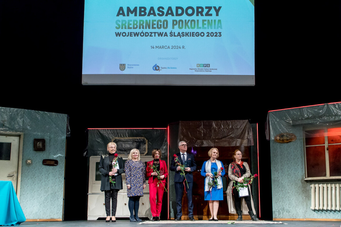 Mężczyzna w niebieskim dresie trzyma tradycyjny polski kufel, uczestnicząc w uroczystości związanych z programem Ambasadorzy Srebrnego Pokolenia. (wygenerowano przez AI)