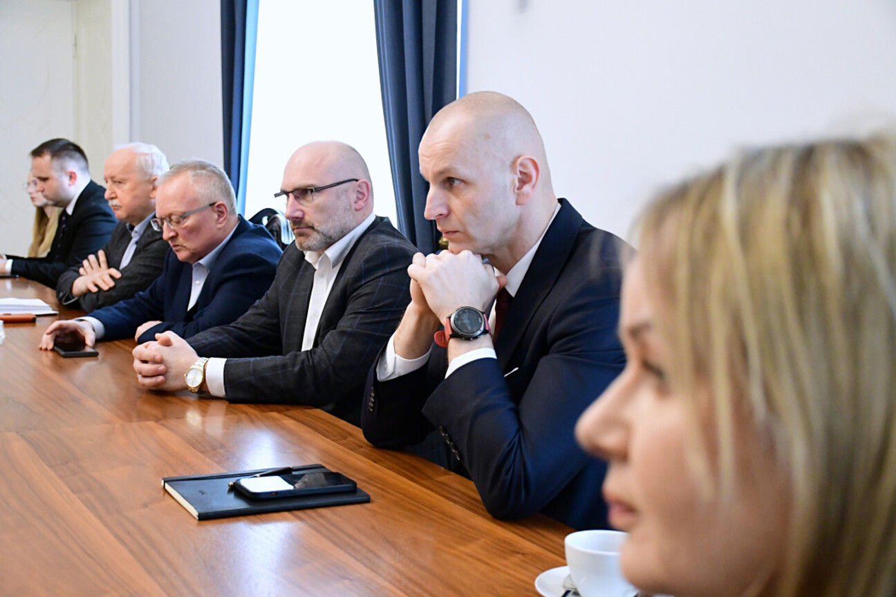 Grupa mężczyzn w formalnym stroju omawia dokumenty, podczas spotkania w Gmachu Sejmu Śląskiego. (wygenerowano przez AI)