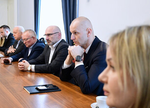 Grupa mężczyzn w formalnym stroju omawia dokumenty, podczas spotkania w Gmachu Sejmu Śląskiego. (wygenerowano przez AI)