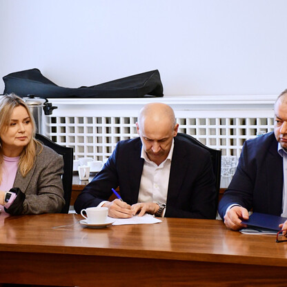 Grupa ludzi w formalnym spotkaniu w Sali Błękitnej Gmachu Sejmu Śląskiego, omawiając reaktywację połączenia kolejowego Gliwice-Rybnik. (wygenerowano przez AI)