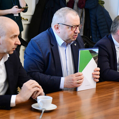 Grupa mężczyzn w formalnym stroju omawia dokumenty, podczas spotkania w Gmachu Sejmu Śląskiego. (wygenerowano przez AI)
