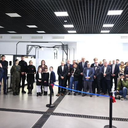 Wernisaż Krajowego Centrum Bezpieczeństwa Ruchu Drogowego w Katowicach. Uczestnicy w strojach formalnych, słuchań przemówienia. (wygenerowano przez AI)