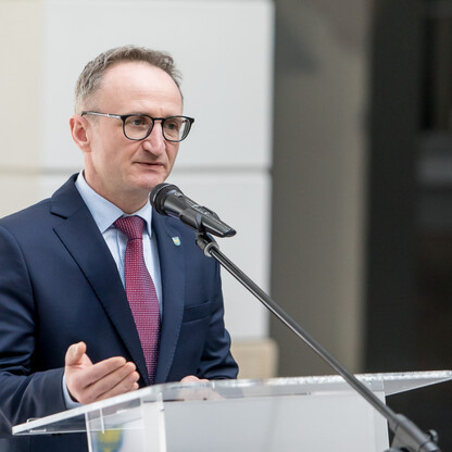 Grzegorz Boski, wicemarszałek województwa, przemawia na podium podczas ceremonii przekazania funduszy na drogi dojazdowe do gruntów rolnych. (wygenerowano przez AI)