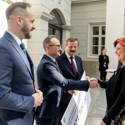 Grzegorz Boski, wicemarszałek województwa, prezentuje symboliczne czeki na modernizację dróg dojazdowych do gruntów rolnych w Bielsku-Białej. (wygenerowano przez AI)