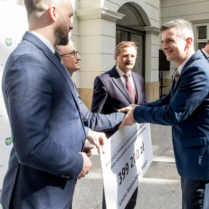 Wicemarszałek Województwa Śląskiego Grzegorz Boski prezentuje symboliczne czeki na modernizację dróg dojazdowych do gruntów rolnych w Książąt Sułkowskich Castle. (wygenerowano przez AI)