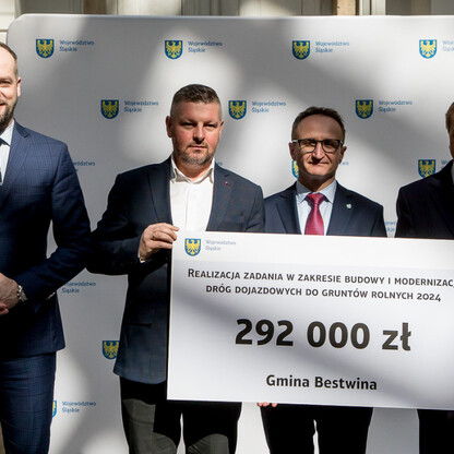 Grzegorz Boski, wicemarszałek, prezentuje symboliczny czek na modernizację dróg dojazdowych do gruntów rolnych w Śląskim. (wygenerowano przez AI)