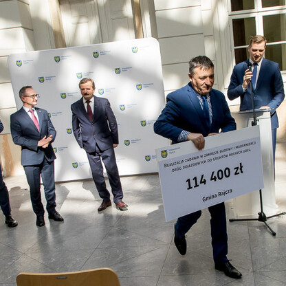 Grzegorz Boski, wicemarszałek województwa, przekazuje symboliczny czek na modernizację dróg dojazdowych do gruntów rolnych w Silesii. (wygenerowano przez AI)
