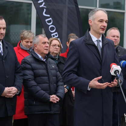Grupa ludzi w formalnym stroju omawia projekt Tyskiego HUB dla zielonej gospodarki. (wygenerowano przez AI)