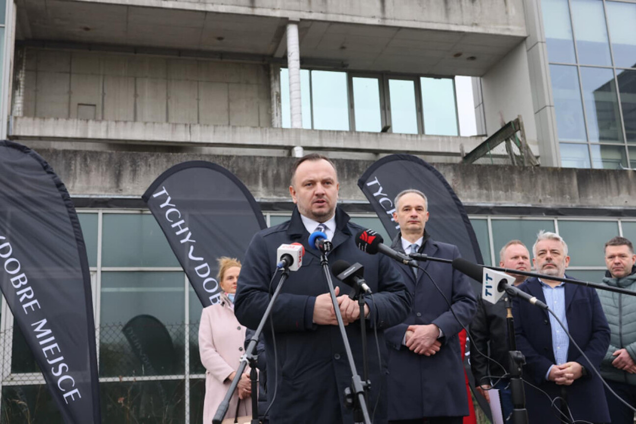 Mężczyzna w rozmowie z dziennikarzem przed modernnym budynkiem. Projekt Tyskiego HUB dla zielonej gospodarki. (wygenerowano przez AI)