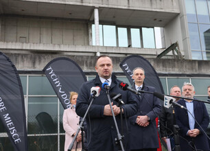 Mężczyzna w rozmowie z dziennikarzem przed modernnym budynkiem. Projekt Tyskiego HUB dla zielonej gospodarki. (wygenerowano przez AI)